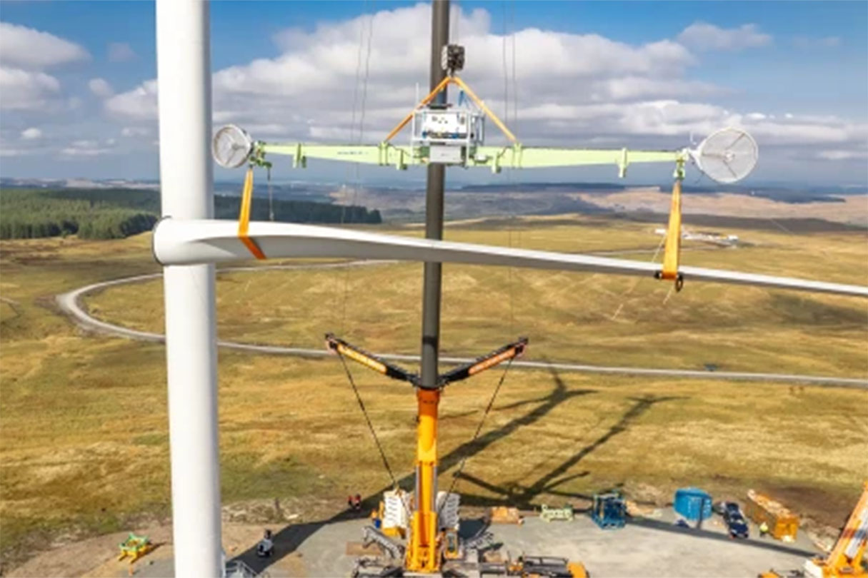 wind turbine installation - a crane hoisting a blade into position